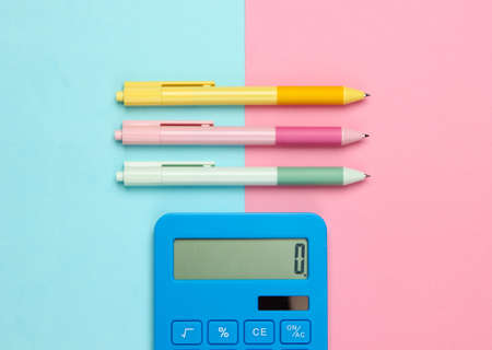 Blue calculator with colored pens on a pink blue pastel background. Top view. Office tools. Economistの写真素材