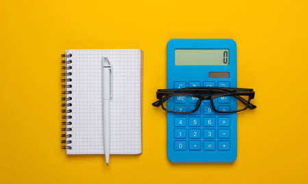 Calculator and glasses, notebook on yellow background. Secretary, economist or office worker...