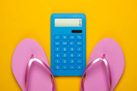 Calculation of the cost of vacation at sea or ocean beach. Calculator with flip flops on a yellow background. Top view. Flat layの写真素材