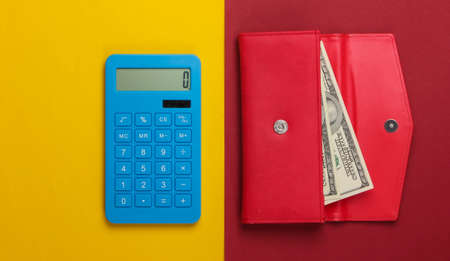 Manage family budget. Shopping costs. Blue calculator and red leather wallet with dollar bills on yellow red background. Top viewの写真素材