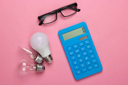 Energy saving. Calculator with light bulbs, glasses on pink blue pastel background. Top viewの写真素材