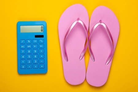 Calculation of the cost of vacation at sea or ocean beach. Calculator with flip flops on a yellow background. Top view. Flat layの写真素材