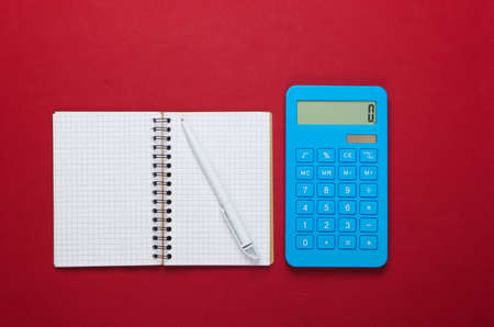Calculator with notebook on red background. Education process. Top view. Flat layの写真素材