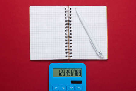 Calculator with notebook on red background. Education process. Top view. Flat lay