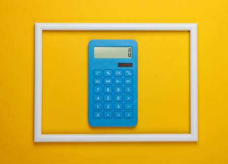 Calculator in a white frame on a yellow background. Concept art photo. Top view. Minimalismの写真素材