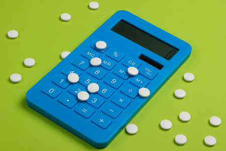 Calculation of the cost of medical expenses. Calculator and pills on green background. Top view....