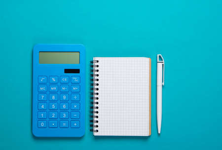 Calculator with notebook on blue background. Education process. Top view. Flat layの写真素材