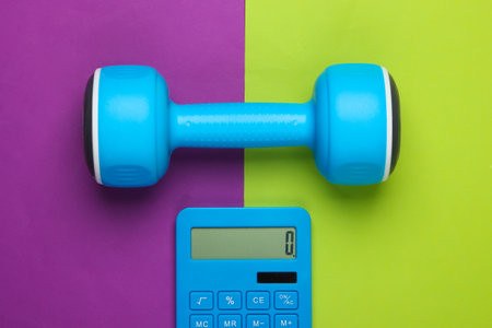 Fitness, weight loss still life. Calorie Counting. Calculator and dumbbell on green purple background. Minimalism. Flat layの写真素材