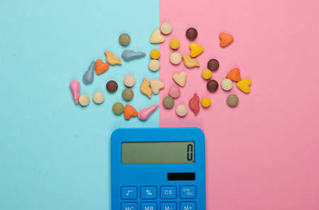 Calculator and vitamins for animals on a blue-pink pastel background. Veterinary concept. Top viewの写真素材