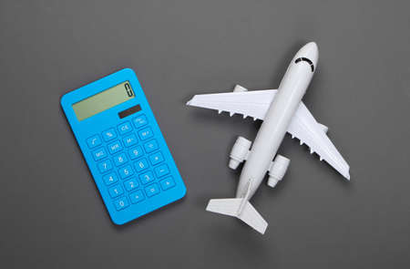Calculator and figurine of a passenger plane on a gray background. Calculation of the cost of air travel. Top viewの写真素材