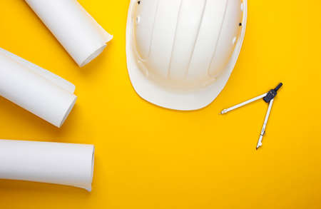 Engineering construction safety helmet, drawing rolls, compass on yellow background. Building house....