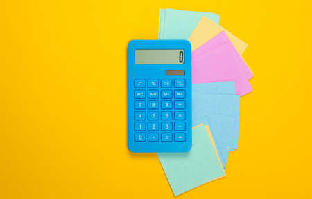 Calculator with memo pieces of paper on a yellow background. Top viewの写真素材