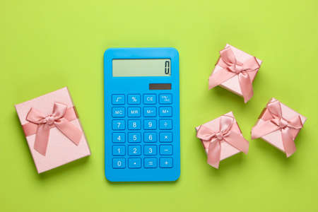 Calculator and gift boxes with a bow on green background. Calculation of the value of the gift. Top view.の写真素材