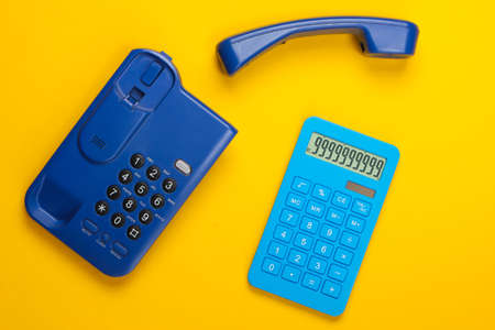 Calculator with a stationary office phone on yellow background. Top viewの写真素材
