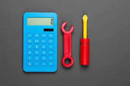 Calculation of the cost of repair work. Calculator and toy wrench and screwdriver on gray...
