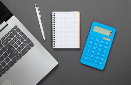 Calculator with notebook and laptop on gray background. family budget management. Top viewの写真素材