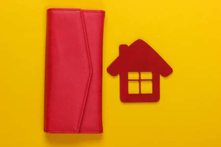 Family budget management. Figurine of a house with wallet on yellow background. Top viewの写真素材