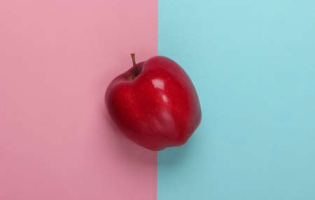 Red apple on a blue-pink pastel background. Top view