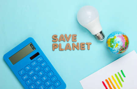 Eco concept. Save the planet. Globe and led light bulb, globe, calculator, energy efficiency rating on blue background. Top viewの写真素材