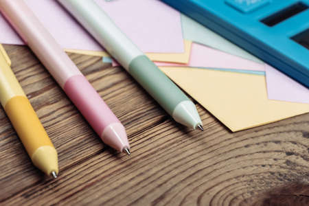 Calculator with memo papers and colored pens on a wooden table.の写真素材