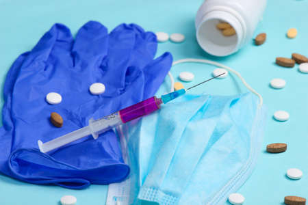 Medical supplies. Syringe, medical gloves, mask, pills on a blue background.の写真素材