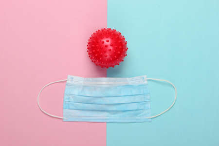 Coronavirus protection. Facial medical mask and strain of the virus on a pink blue pastel...