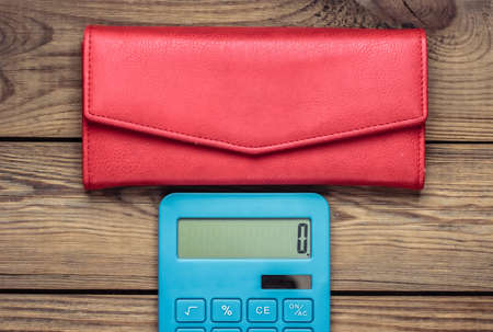Calculator with leather wallet on wooden table. Shopping Cost Calculation