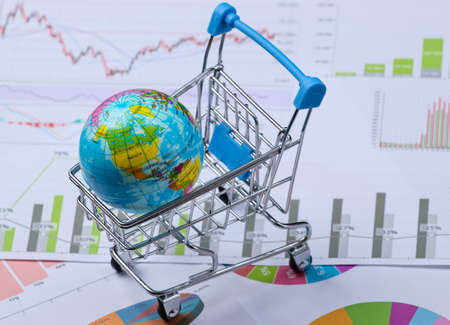 Globe in a shopping cart on graphs and charts.の写真素材