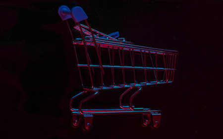 Shopping trolley with neon red-blue light on a black background. Shopping conceptの写真素材