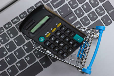 Calculation of the cost of online purchases. Shopping trolley with calculator on keyboardの写真素材