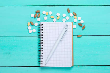 Pills with notebook on blue wooden background. Top viewの写真素材