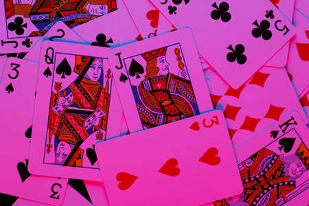 Playing cards in neon blue-pink light on black background. Game addiction. Pokerの写真素材