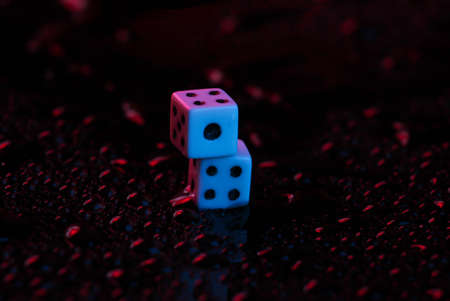 Dice in blue-red neon light on a dark background with drops of waterの写真素材