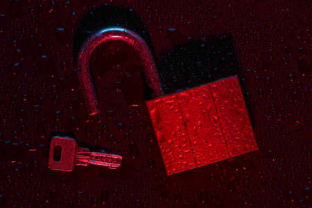 Lock with a key and drops of water in a neon red light. Data protectionの写真素材