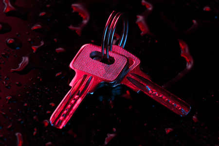 Keys in blue-red neon light on a dark background with water drops.の写真素材