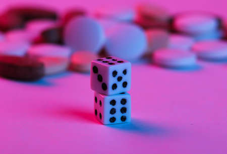 Dice and pills in blue-red neon light. Game addiction treatmentの写真素材