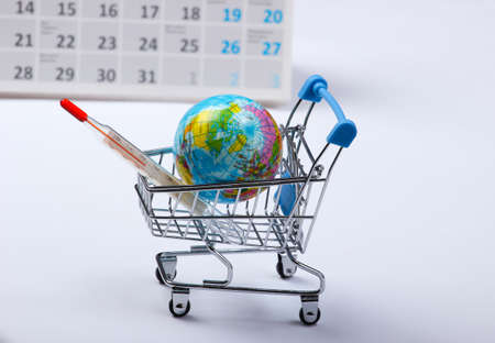 Save the planet. Global warming concept. Shopping trolley with a globe and a thermometer on a white background with a calendar. Earth dayの写真素材