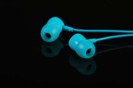 Blue vacuum earphones on a black background close-up