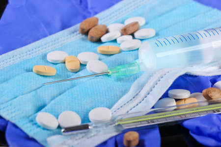 Medical still life. Syringe, thermometer, medical mask with gloves, pills. Diagnosis, protection and...