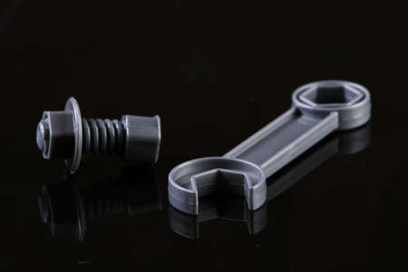 Gray plastic wrench with nut and bolt on a black background