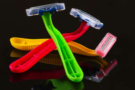 Colored plastic razors on a black background with reflectionの写真素材