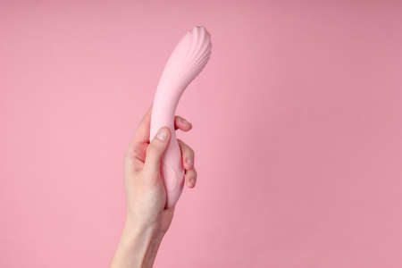 hand holding Sex toy for women on pink background.の写真素材