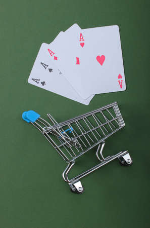 Shopping trolley with four aces on a green background. Top viewの写真素材