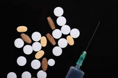 Syringe with pills on a black background. Treatment, vaccinationの写真素材