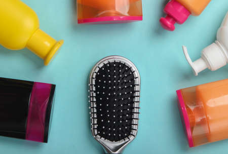 Hair brush with shampoo bottles on blue pastel background. Hair care. Hygiene. Beauty flat lay. Top viewの写真素材