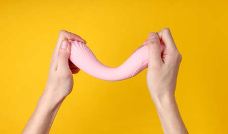 hand holding Sex toy for women on yellow background.の写真素材