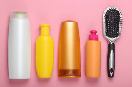 Hair brush with shampoo bottles on pink pastel background. Hair care. Hygiene. Beauty flat lay. Top viewの写真素材