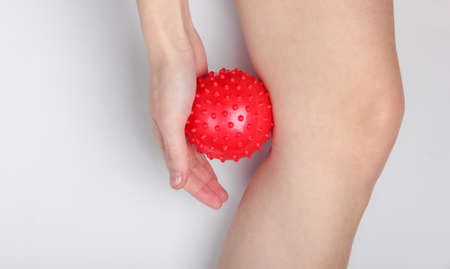 Woman massages a massage ball under her knee.の写真素材