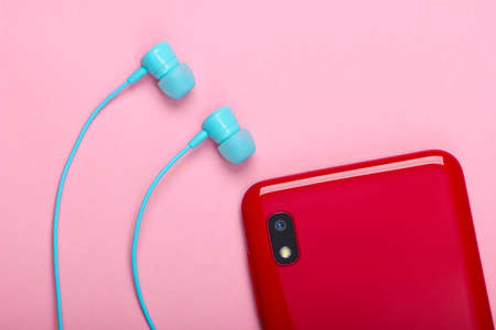 Smartphone with vacuum earphones on pink background. Top viewの写真素材