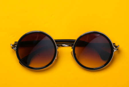 Stylish fashionable round sunglasses on yellow paper background. Top view. Minimalismの写真素材